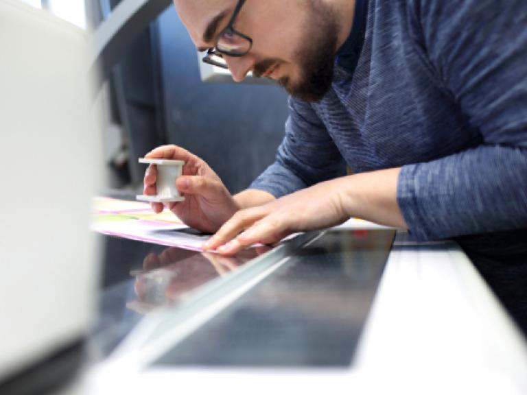 Image of a man with a loupe, ensuring high quality print embellishments with thorough quality control